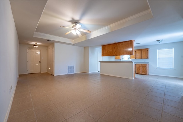 unfurnished living room featuring a raised ceiling, ceiling fan, crown molding, and light tile patterned flooring