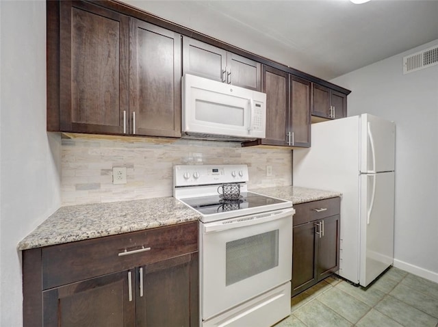 kitchen featuring light tile patterned flooring, backsplash, dark brown cabinets, light stone countertops, and white appliances