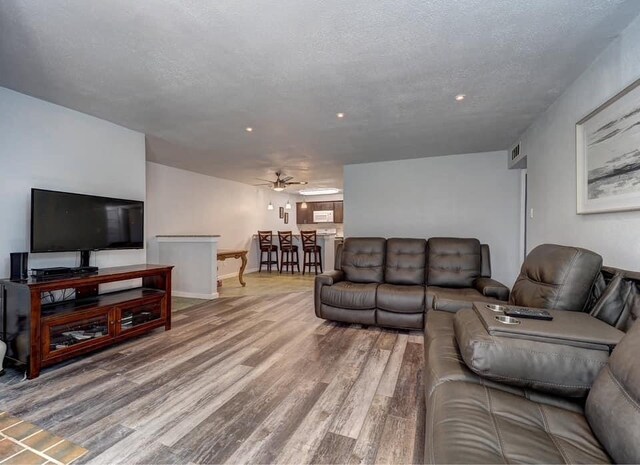 living room featuring hardwood / wood-style floors, a textured ceiling, and ceiling fan