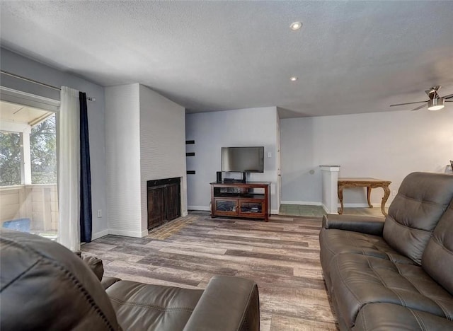 1011 Ennis Joslin Unit 224, Corpus Christi, TX 78412 - living room featuring wood finished floors, a ceiling fan, a fireplace, baseboards, and a textured ceiling