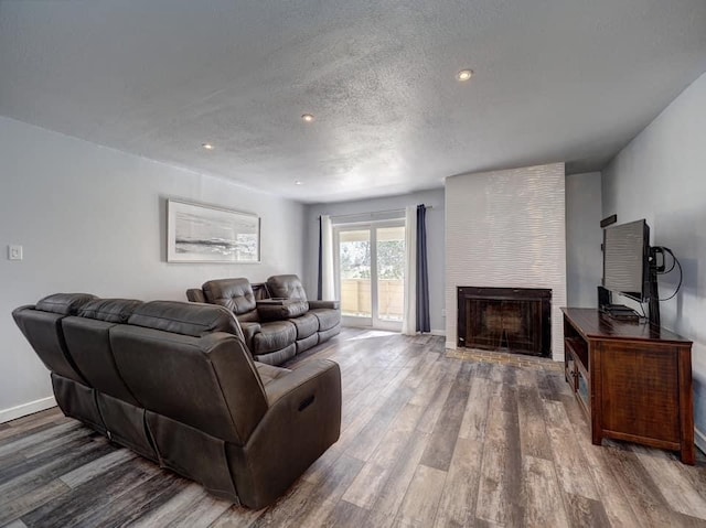 living room with a fireplace, hardwood / wood-style flooring, and a textured ceiling