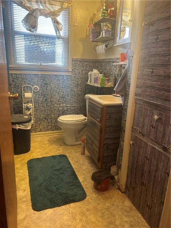 bathroom featuring tile walls, vanity, and toilet