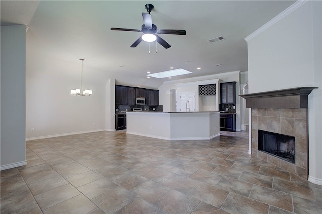 interior space with sink, crown molding, a skylight, a fireplace, and ceiling fan with notable chandelier