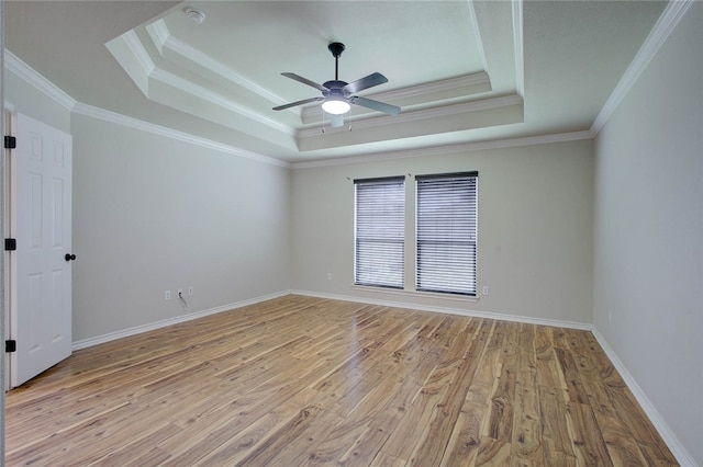 empty room featuring ceiling fan, ornamental molding, a raised ceiling, and light hardwood / wood-style floors