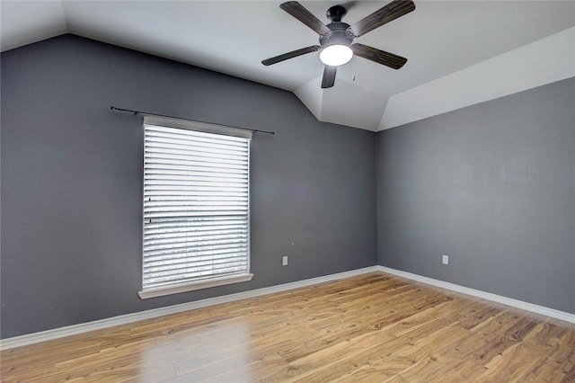 spare room featuring lofted ceiling, a healthy amount of sunlight, and light hardwood / wood-style floors