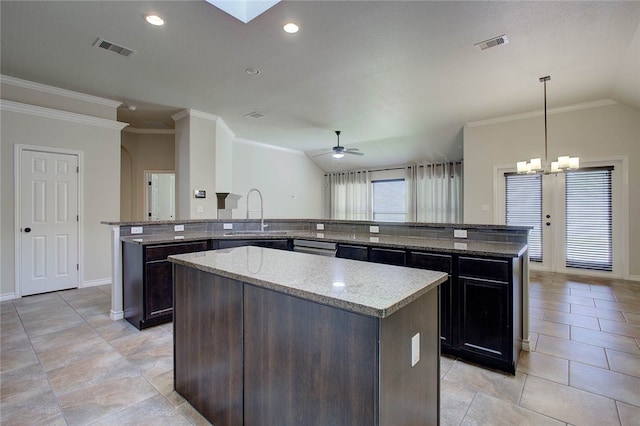 kitchen with a kitchen island, ceiling fan with notable chandelier, sink, hanging light fixtures, and light stone counters