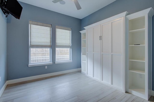 unfurnished bedroom featuring baseboards, a closet, a ceiling fan, and light wood-style floors