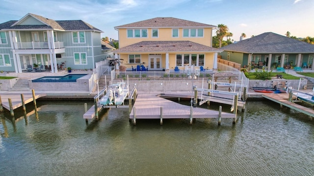 back of property featuring boat lift, a water view, a patio area, a fenced backyard, and an outdoor pool