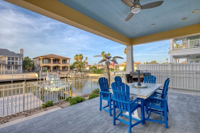 view of patio with ceiling fan, outdoor dining space, a water view, and fence