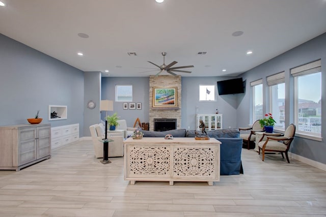 living area featuring a stone fireplace, visible vents, and light wood-style floors