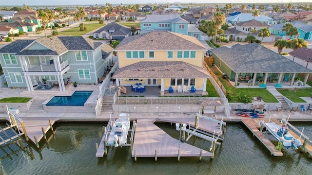 dock area with a water view, a patio area, boat lift, and a residential view