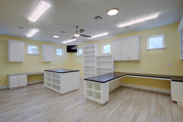 unfurnished office featuring ceiling fan, light wood-style flooring, visible vents, baseboards, and built in study area