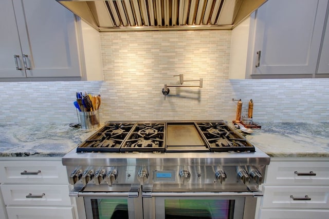 kitchen with premium range hood, decorative backsplash, white cabinetry, and double oven range