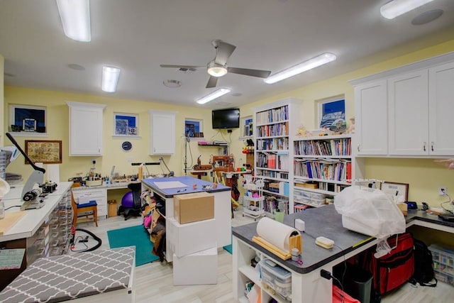 home office featuring visible vents, light wood finished floors, and a workshop area