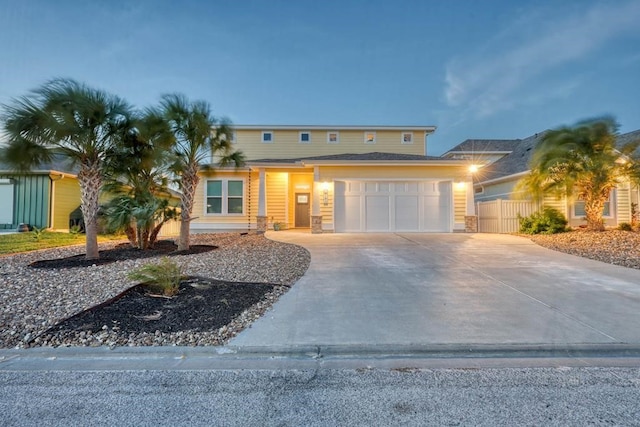 view of front of property featuring an attached garage, fence, and concrete driveway