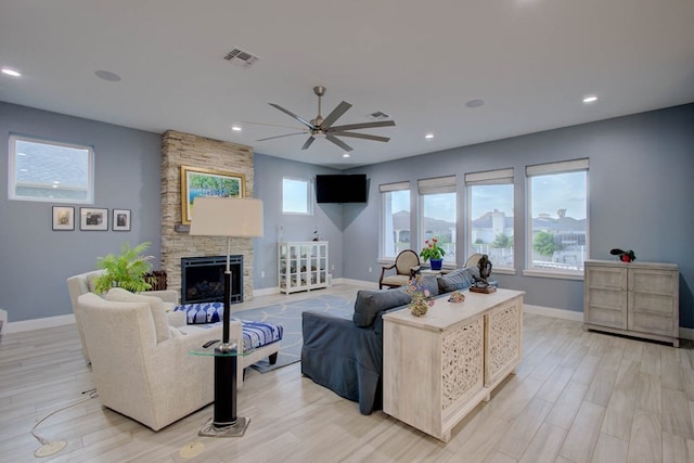 living area featuring light wood-type flooring, visible vents, a fireplace, and baseboards