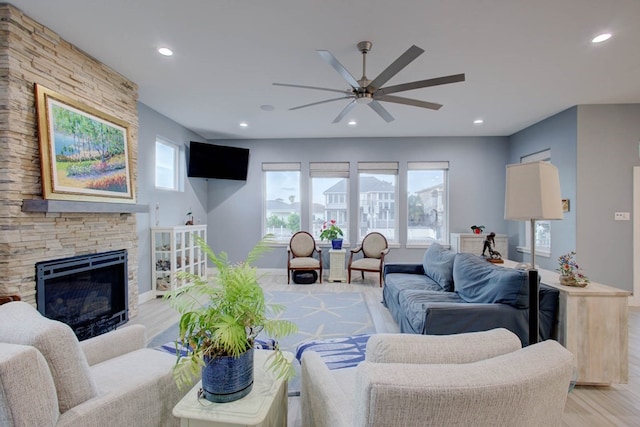 living area with a fireplace, light wood finished floors, recessed lighting, ceiling fan, and baseboards