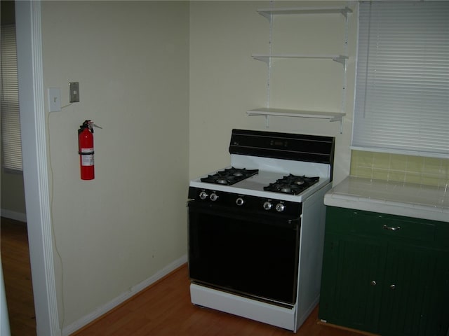 kitchen with tile countertops, gas range gas stove, and light wood-type flooring