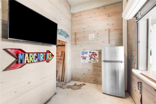 133 Barnacle Dr, Rockport, TX 78382 - kitchen featuring wooden walls, unfinished concrete flooring, and freestanding refrigerator
