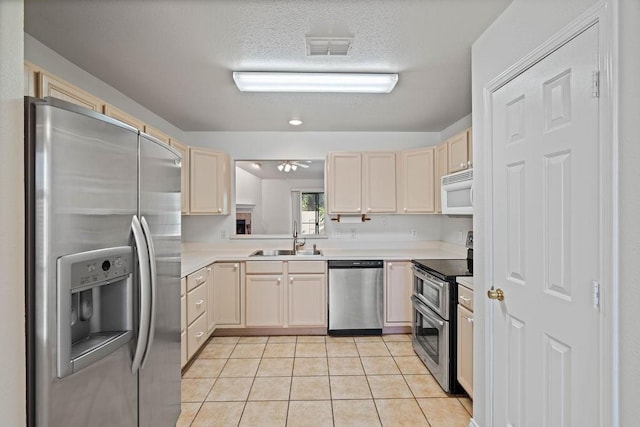 kitchen with light tile patterned flooring, appliances with stainless steel finishes, sink, and a textured ceiling