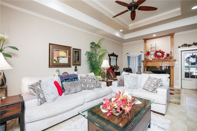 living room featuring light tile patterned flooring, ceiling fan, a raised ceiling, and ornamental molding