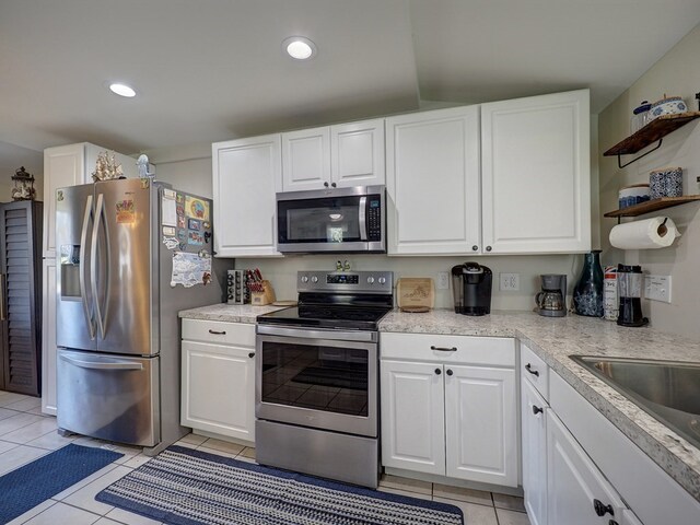 kitchen with sink, white cabinetry, light tile patterned floors, and appliances with stainless steel finishes