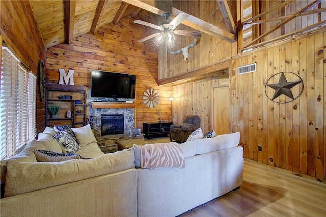 living room with a fireplace, wooden walls, hardwood / wood-style flooring, beamed ceiling, and wooden ceiling