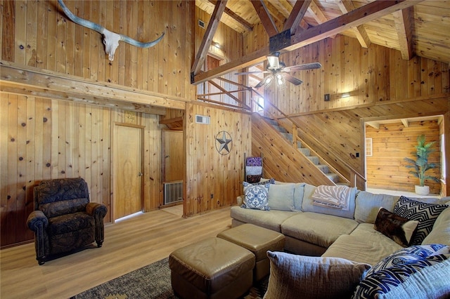 living room featuring high vaulted ceiling, wood walls, wood-type flooring, and beam ceiling