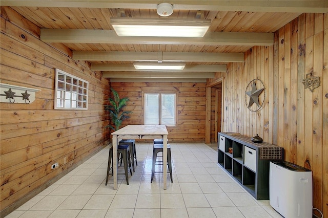 unfurnished dining area with wood walls, beamed ceiling, wooden ceiling, and light tile patterned flooring