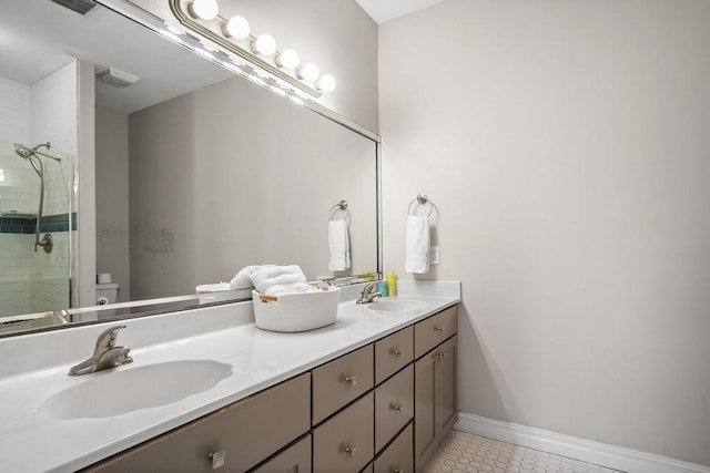 bathroom with tiled shower, vanity, toilet, and tile patterned floors