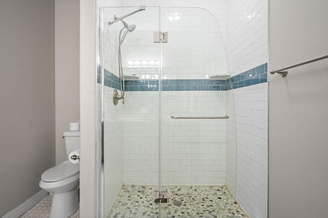 bathroom with a shower with shower door and toilet