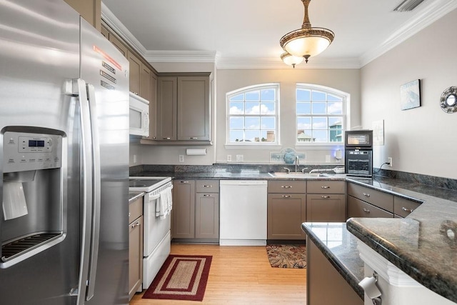 kitchen featuring sink, white appliances, crown molding, dark stone countertops, and decorative light fixtures