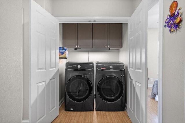 laundry area with cabinets, light wood-type flooring, and washing machine and clothes dryer