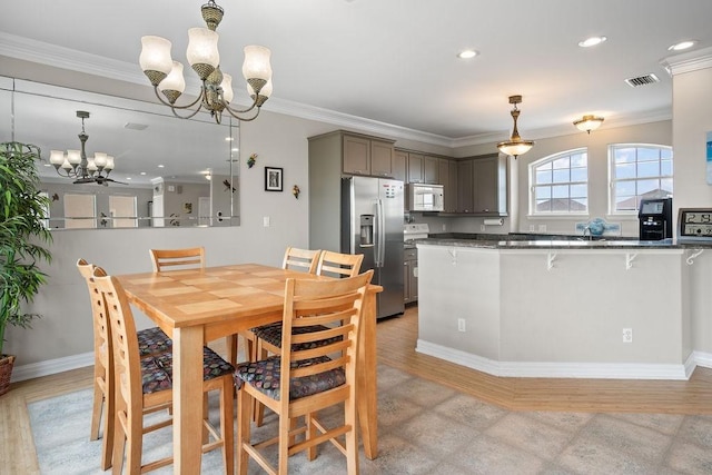 dining space with crown molding, light hardwood / wood-style floors, and a chandelier