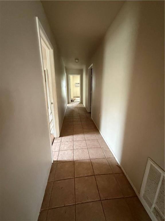 hall with visible vents, baseboards, and tile patterned floors