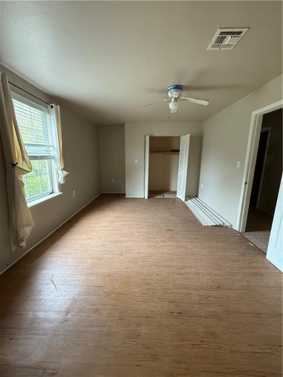 unfurnished bedroom featuring ceiling fan, visible vents, baseboards, a closet, and light wood finished floors