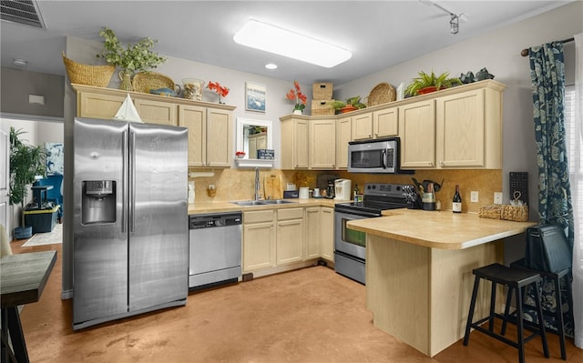 kitchen with stainless steel appliances, sink, decorative backsplash, and kitchen peninsula