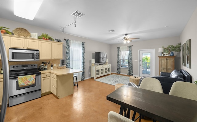 kitchen featuring appliances with stainless steel finishes, track lighting, a breakfast bar area, kitchen peninsula, and ceiling fan