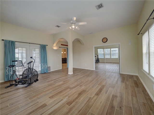 unfurnished living room featuring french doors, light wood-type flooring, a wealth of natural light, and ceiling fan