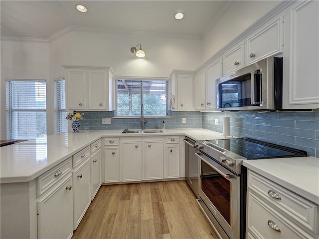 kitchen with white cabinets, backsplash, kitchen peninsula, and stainless steel appliances