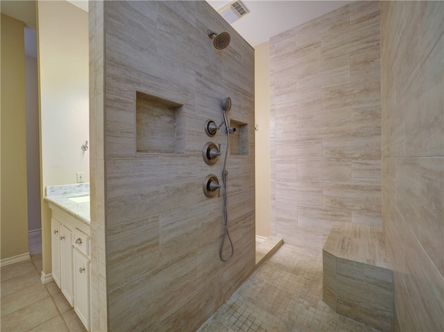 bathroom with tile walls, vanity, tile patterned floors, and a tile shower