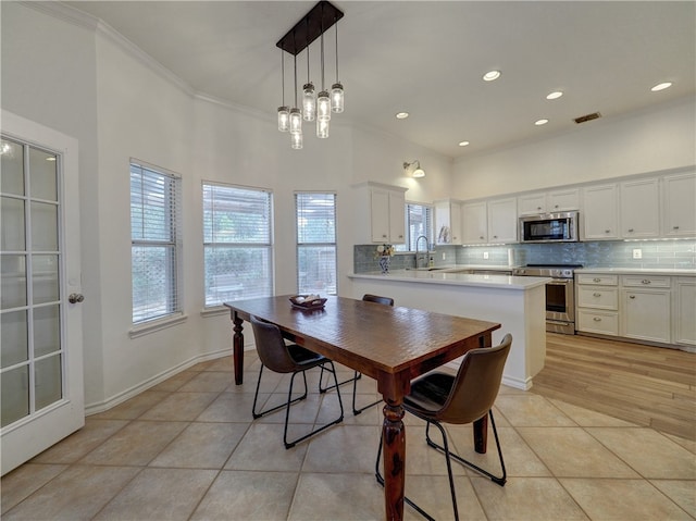 dining area with sink, light tile patterned floors, and ornamental molding