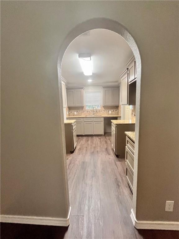 630 Sharon Dr, Corpus Christi, TX 78412 - kitchen with arched walkways, backsplash, light wood-style flooring, and light countertops