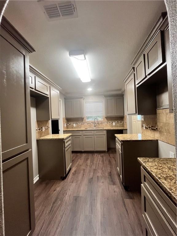 630 Sharon Dr, Corpus Christi, TX 78412 - kitchen with dark wood-style flooring, decorative backsplash, and light stone counters