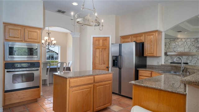 kitchen with sink, a chandelier, stone counters, pendant lighting, and appliances with stainless steel finishes