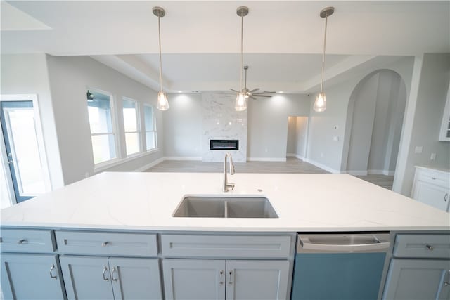 kitchen featuring light stone counters, sink, a high end fireplace, and an island with sink