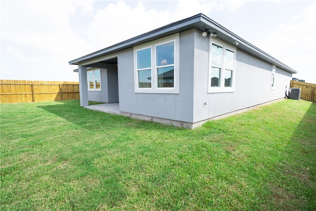 view of side of property featuring cooling unit and a lawn