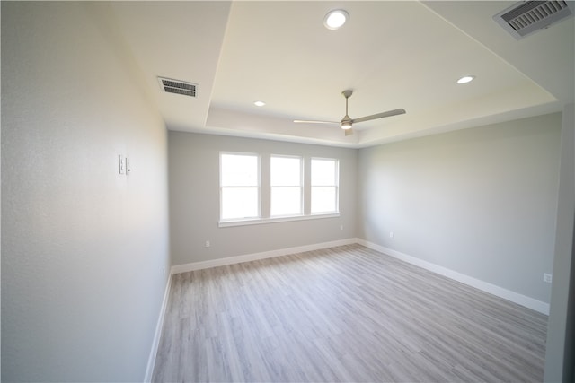 empty room featuring light hardwood / wood-style floors, a raised ceiling, and ceiling fan