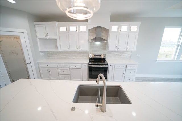 kitchen with white cabinetry, wall chimney exhaust hood, stainless steel range with electric cooktop, and light stone counters