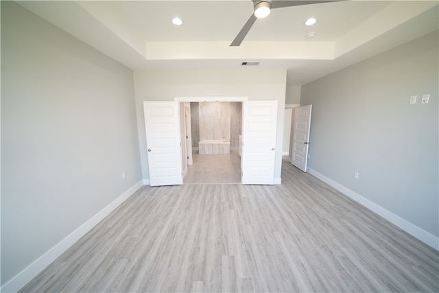 unfurnished bedroom with a tray ceiling, light hardwood / wood-style flooring, and ceiling fan